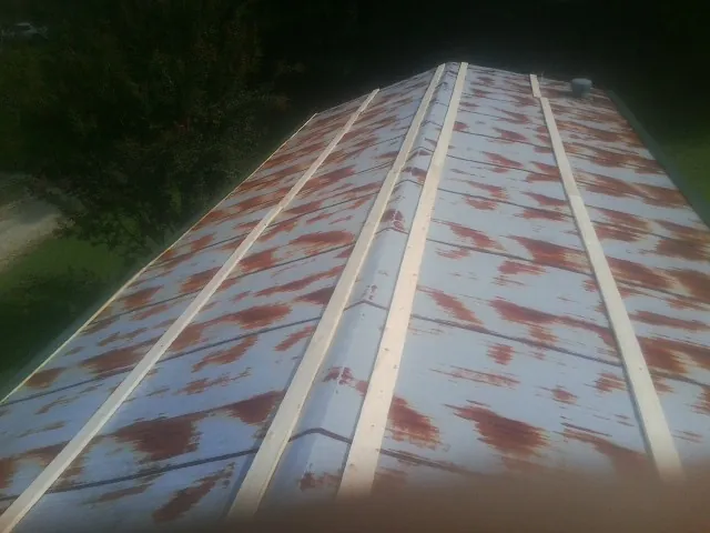 Rusted metal roof panels with new wood purlins before replacement — Storm Damage Roof Repair in Victor by Roofing Brothers