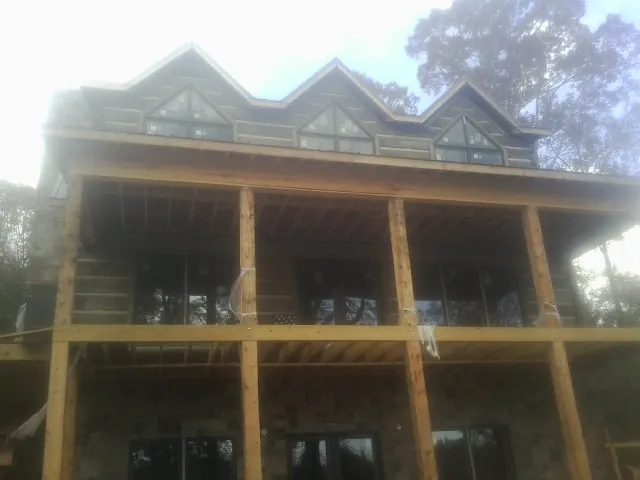 Dormers and porch framing on a large log home under construction — Roof Coating work by our crew in Victor