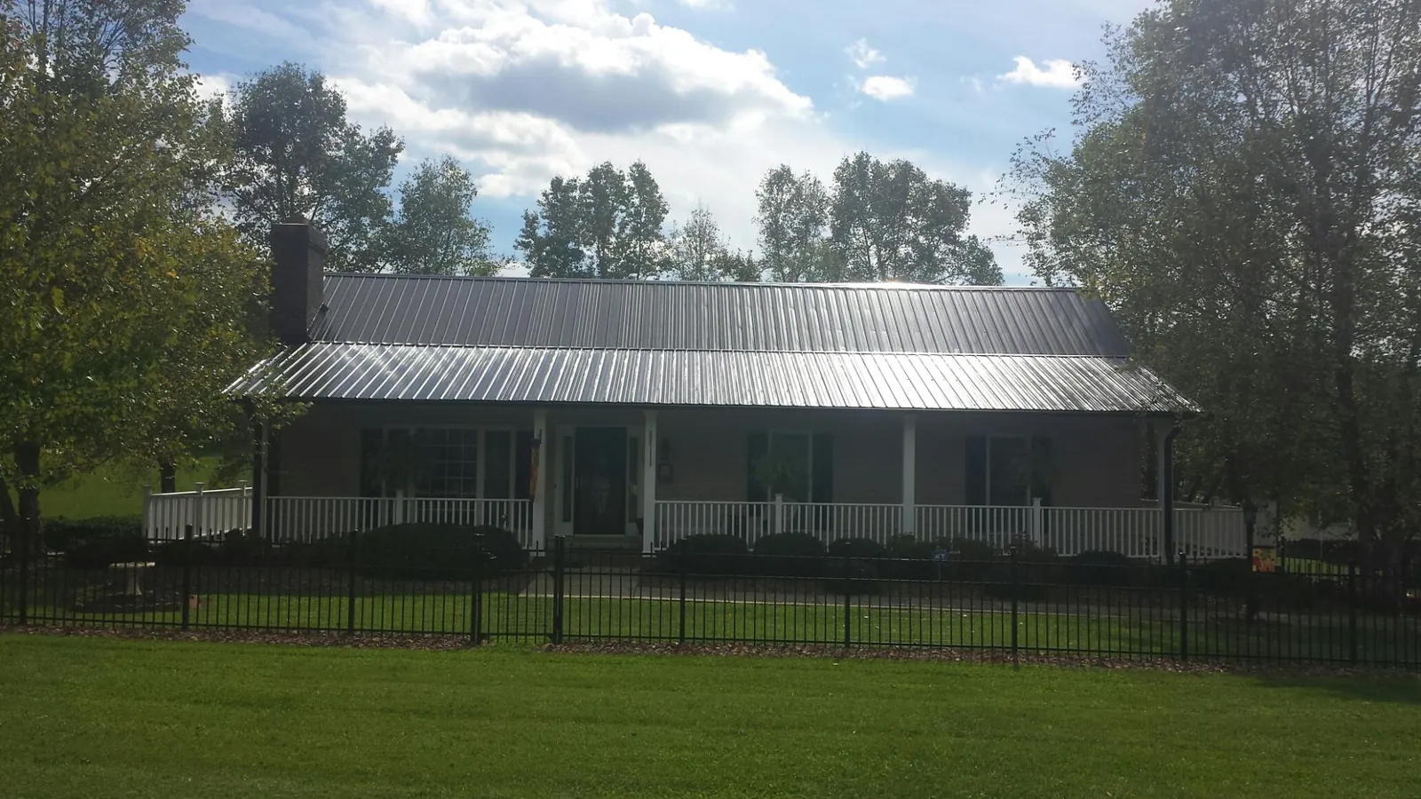 Gray metal roof on a brick ranch with a full width front porch — Gutter Guard Installation work by our crew in Victor